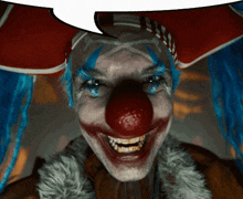 a clown with blue hair and a red hat is smiling with a speech bubble above his head