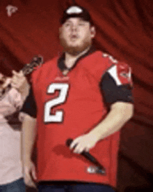 a man in a red football jersey is holding a microphone .