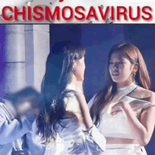 two women are standing next to each other in front of a sign that says ' chismosaurus ' on it .