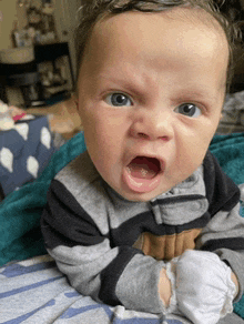 a baby is making an angry face with his mouth wide open