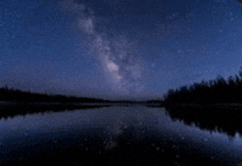 the milky way is reflected in the lake at night .