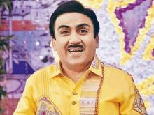 a man wearing a yellow shirt and a mustache is smiling .