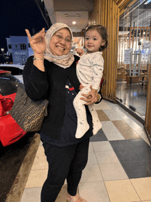 a woman holding a baby with a fendi bag behind her