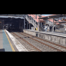 a train is pulling into a train station with people waiting on the platform