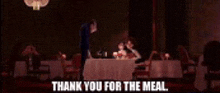 a man is standing in front of a table with a woman sitting at it and says `` thank you for the meal '' .