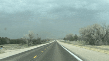 a highway with trees on both sides and a cloudy sky