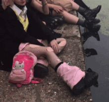 a girl with a pink hello kitty backpack sits next to a group of people