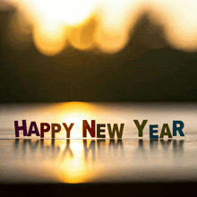 the words happy new year are on a table in front of a sunset