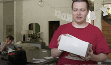 a man in a red shirt is holding a white box in front of a banner that says " edv "