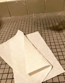 two white paper towels on a tiled floor