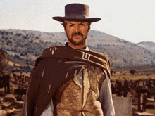 a man with a beard wearing a cowboy hat and a blanket with the letter t on it