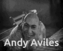 a black and white photo of a man with a flower on his head and the name andy aviles .