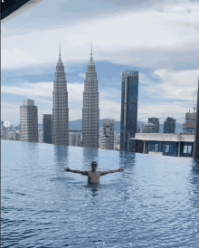 a man is swimming in an infinity pool with a view of the city skyline