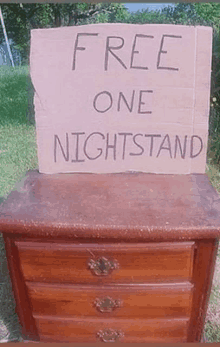 a cardboard sign on top of a wooden nightstand that says free one nightstand