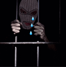 a man in a ski mask behind bars with tears coming out of his eyes