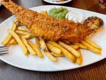 a plate of fish and chips with a fork on a table .