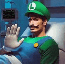 a man dressed as luigi is laying in a hospital bed waving .