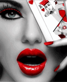 a woman with red lips is holding a king of hearts playing card in front of her face