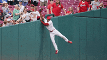 a baseball player wearing a bengals jersey leaps over a fence