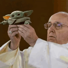 the pope is holding a stuffed animal in his hands .