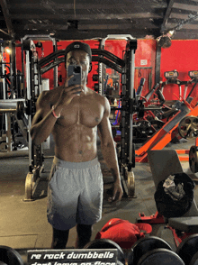 a man taking a selfie in a gym with a sign that says rack dumbbells on the floor