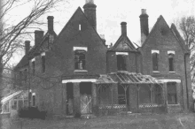 a black and white photo of a large brick house with chimneys .