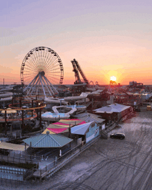 a ferris wheel sits in the middle of a water park at sunset