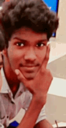 a close up of a young man 's face with his hand on his chin .