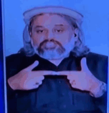 a man with long hair and a beard is pointing at something with his hands .