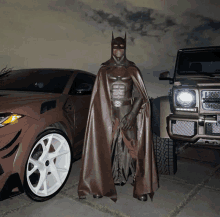 a man in a batman costume is standing next to a car