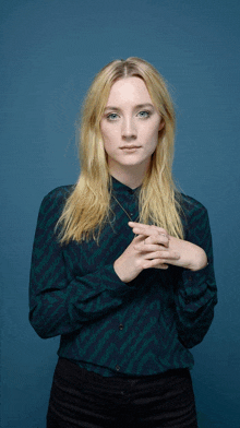 a woman with blonde hair and blue eyes is wearing a green shirt