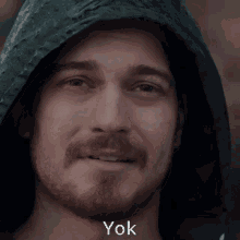 a man with a beard is wearing a hooded jacket and the word yok is on the bottom