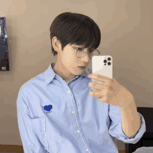 a man taking a picture of himself in a mirror with a blue heart on his shirt