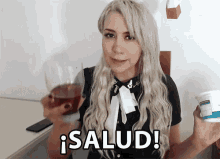 a woman is holding a glass of wine and a bottle of yogurt and the word salud is on the screen