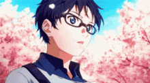 a young boy wearing glasses is standing in front of a cherry blossom tree .