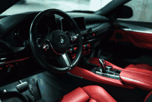 the interior of a bmw with red seats and a steering wheel