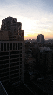 a sunset over a city with a few buildings in the foreground and a few in the background