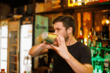 a man in a black shirt is shaking a drink in front of a corona beer fridge