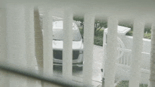 a white car is parked in a driveway next to a white fence .