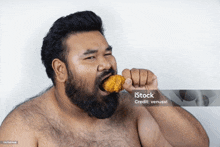 a man with a beard is eating a fried chicken wing