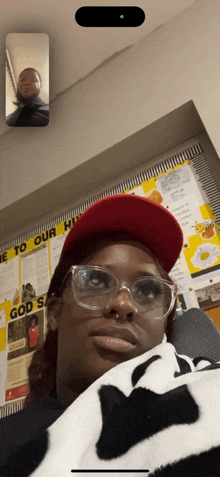 a woman wearing glasses and a red hat is sitting in front of a sign that says " welcome to our home "