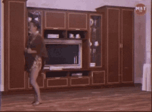 a woman is dancing in front of a tv in a living room with the word mat on the bottom