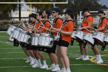 a marching band is playing their drums on a field and their shirts say ip