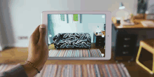 a person holding a tablet with a couch on the screen