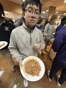 a boy wearing glasses holds a plate of food in front of a sign that says milk