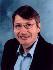 a man with glasses and a blue shirt is smiling for the camera