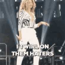 a woman is standing on a stage with a microphone in her hand and the words `` itwirl on them haters '' .