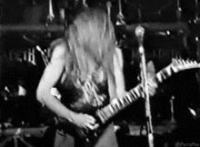 a man is playing a guitar on stage in a black and white photo .