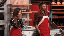 a man and a woman wearing santa aprons are standing in a kitchen with a netflix logo in the corner