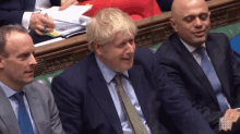 a man in a suit and tie is smiling while sitting next to two other men in suits and ties